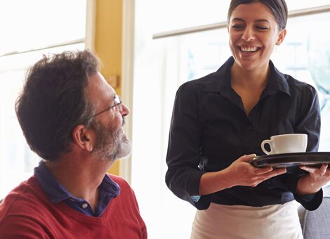 Woman Serving Cup of Coffee to Customer