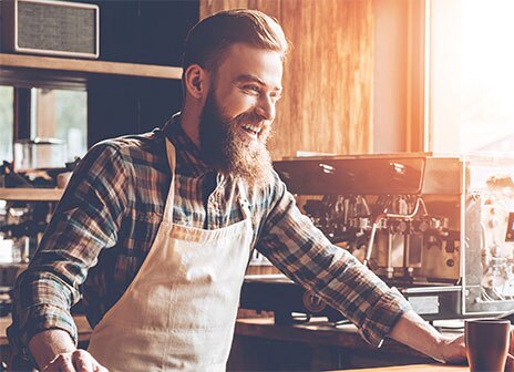 Barista Laughing at Bar in Front of Coffee Equipment