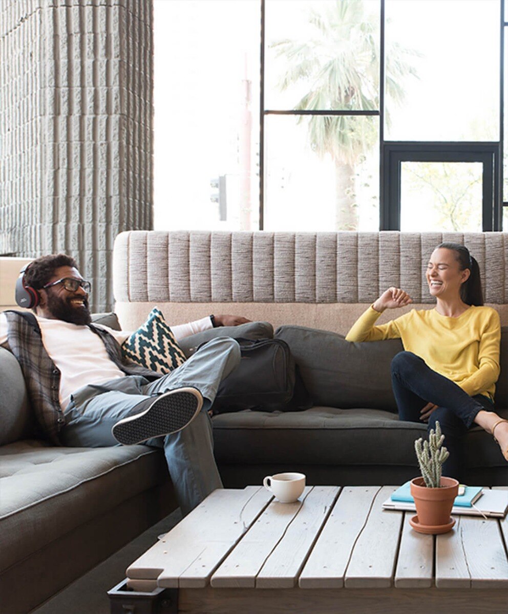 Man & Woman Sitting on Couches Enjoying Coffee in a Residential Community Lounge