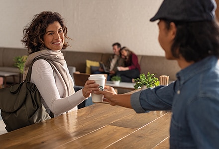 Barista Handing Starbucks Coffee Cup to Woman in Hotel Barista Handing Starbucks Coffee Cup to Woman in Hotel