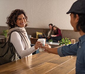 Barista Handing Starbucks Coffee Cup to Woman in Hotel Barista Handing Starbucks Coffee Cup to Woman in Hotel