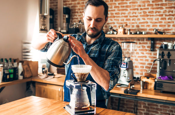 Man Pouring Coffee in We Proudly Serve Starbucks Cafe